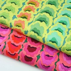 two colorful fabric pieces on top of each other, one with different colors and shapes