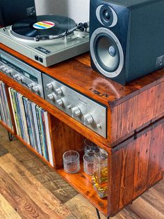 a record player sitting on top of a wooden shelf next to a stereo and speakers