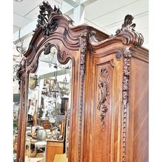 an ornate wooden bed frame with mirror on the top, and other furniture in the background