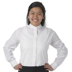 a woman standing with her hands on her hips wearing a white shirt and black pants