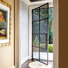 an open door leading into a room with wood flooring and framed pictures on the wall