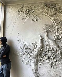 a man standing in front of a wall with a peacock on it