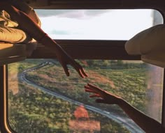 two people reaching out the window of a train to touch each other's hand