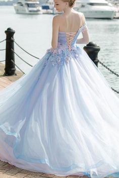 a woman in a blue and white dress standing on a dock