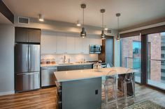 a kitchen with stainless steel appliances and an island in front of a large sliding glass door