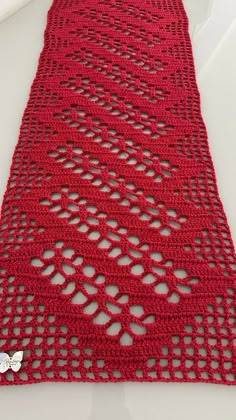 a red crocheted table runner on a white surface