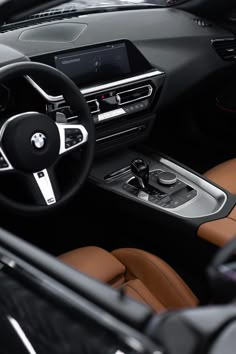 the interior of a bmw car with brown leather seats and steering wheel, including an electronic display