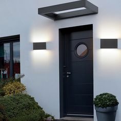 a black front door with two lights and a potted plant