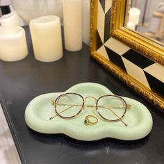 a pair of glasses sitting on top of a green plate in front of a mirror