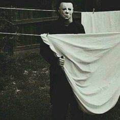 a man holding up a white cloth on a clothes line