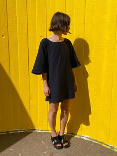 a woman standing in front of a yellow wall