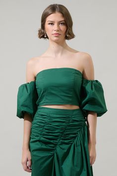 Turn heads when you are wearing the Jadey Elvie Smocked Cropped Top. Fresh cotton fabric creates a straight neckline and puff sleeves with elastic at the arms and cuffs, giving it the off the shoulder look. The back is smocked for comfier fit. Pair with the matching skirt for a complete look.- Off the shoulder- Smocked bodice- Cropped- Bubbled sleeves- Color: EmeraldSize + Fit - Model is 5'8" and wearing size XS- Measurements taken from size S - Chest: 14"- Length: 9 1/2" Fabric Self:100% Cotton Brunch Puff Sleeve Top With Gathered Sleeves, Spring Smocked Lantern Sleeve Top With Elastic Sleeves, Chic Smocked Top With Square Neck And Gathered Sleeves, Spring Long Sleeve Off-shoulder Top With Smocked Bodice, Spring Smocked Top With Puff Sleeves And Ruched Detail, Chic Ruched Balloon Sleeve Top, Fitted Smocked Top With Balloon Sleeves, Summer Balloon Sleeve Top With Smocked Cuffs, Fitted Smocked Top With Balloon Sleeves And Smocked Cuffs