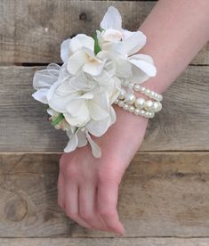 a bride's wrist with flowers and pearls on it