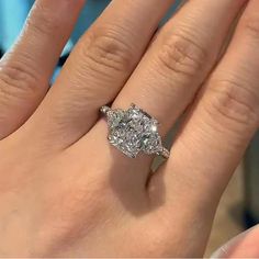 a woman's hand with a diamond ring on top of her finger and the other hand holding an engagement ring