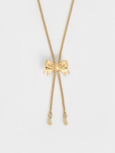 Put the finishing touches to your coquette ensembles with the Paige necklace. The dainty design features an elegant ribbon pendant on a brushed gold-toned chain, imbuing it with a distinctly feminine allure. Equipped with a pull-cord fastening, the necklace can be adjusted to your preferred fit -- you can wear it choker-style for an edgier look, or let it dangle for a softer aesthetic. Formal Gold Necklace With Ribbon, Elegant Gold Necklace With Ribbon, Chic Gold-tone Chain Necklace Choker, Choker Necklace Ribbon, Gold Bow Necklace, Belt Ring, Size Chart For Kids, Ribbon Necklace, Charles Keith