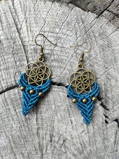 a pair of earrings on top of a piece of wood