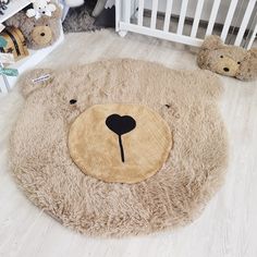 two teddy bears sitting on the floor in front of a baby's crib