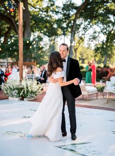 a bride and groom dance together at their outdoor wedding reception in the park on a sunny day