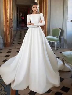 a woman in a white wedding dress standing next to a chair with her hands on her hips