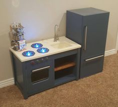 a toy stove and sink in the corner of a room with carpeted flooring