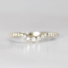 a three stone diamond ring on a white surface, with the band in yellow gold