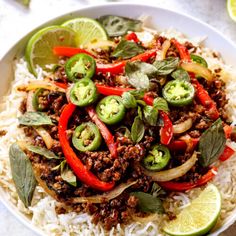 a white bowl filled with rice, meat and veggies next to sliced limes