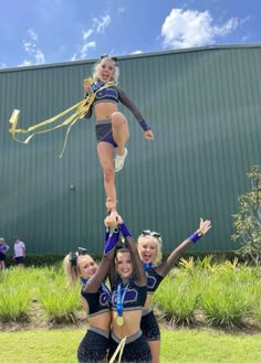 the cheerleaders are doing tricks in front of a building while holding onto each other