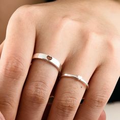 a woman's hand with two rings on her fingers and one ring in the shape of a heart