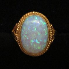 An oval-created opal Ring set in an 18ct Gold and Silver rope edge setting and Shank. Beautifully hand-made by a British professional Jewellery craftsman to the highest standard. Classic Oval Opal Ring Collectible, Heirloom Oval Opal Ring Collectible, Heirloom Oval Cabochon Opal Ring, Classic Oval Hallmarked Opal Ring, Heirloom Oval Opal Ring Hallmarked, Oval Opal Jewelry Collectible, Antique Oval Opal Gemstone Ring, Antique Oval Opal Ring, Collectible Oval Opal Jewelry