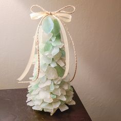 a vase filled with green and white flowers on top of a wooden table next to a wall