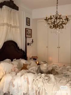 a cat is laying on the bed in a room with white linens and chandelier