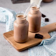 two jars filled with chocolate sitting on top of a cutting board next to each other