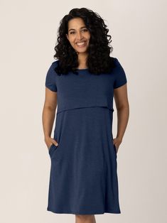 a woman in a blue dress smiling at the camera with her hands on her hips