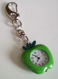 a green apple shaped key chain with a clock on it