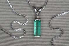 This necklace features a natural earth mined emerald. The emerald was mined in Colombia which is known for producing some of the finest quality emeralds in the world.  It displays an excellent clarity and attractive color. The setting and 18" chain are made of solid sterling silver. The necklace has been certified by Federal Gemological Laboratory Of Canada and the certificate will be included. There emerald is described as follows: Shape and Cut: Baguette Weight: 0.64 ct Species: Natural Beryl Classic Emerald Necklace With Diamond Cut, Hallmarked Round Emerald Necklace, Classic Silver Emerald Cut Emerald Necklace, Classic Emerald Pendant Necklace, Classic Silver Emerald Necklace For May Birthstone, Fine Jewelry Hallmarked Emerald Necklace, Hallmarked Emerald Pendant Necklace, Emerald Cut Gemstone Silver Emerald Necklace, Silver Emerald Cut Gemstone Necklace