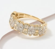 a yellow gold ring with five diamonds on it's sides, sitting on a white surface