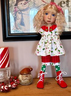 a doll is standing on a table next to candy canes and a framed picture