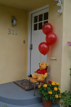 a teddy bear sitting on a chair in front of a door with balloons attached to it