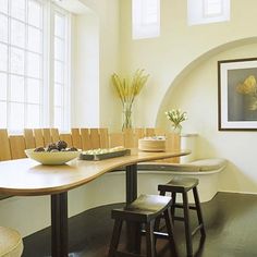 a long table with two stools in front of it and a painting on the wall