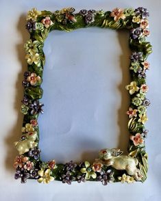 a decorative photo frame with flowers and animals in the shape of a rectangle on a white background