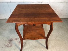 an old wooden table with one drawer on it