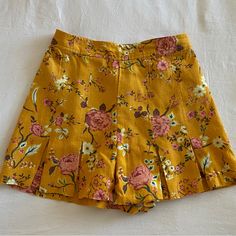 Mustard Yellow Floral Skirt With Front Pleats. 55% Linen And 45% Rayon Never Worn - No Tags Floral Print Mini Bottoms For Vacation, Summer Floral Print Skirted Bottoms, Summer Floral Print Mini Bottoms, Casual Floral Print Mini Shorts, Casual Mini Length Floral Print Shorts, Pleated Mini Bottoms For Summer, Pleated Mini Length Bottoms For Summer, High-waisted Pleated Shorts For A Day Out, Spring Pleated Bottoms With Short Inseam