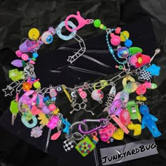 a bracelet with lots of charms on it sitting on top of a piece of black paper