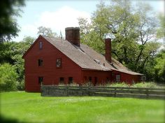 an old red barn sits in the middle of a field