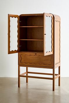 a wooden cabinet with an open door on the front and side, sitting against a white wall