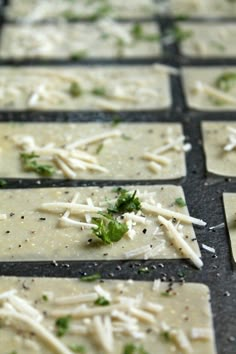 some crackers with cheese and parsley on them are sitting on a pan, ready to be cooked