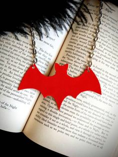 a red bat necklace sitting on top of an open book