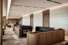 an empty lobby with black leather couches and wooden shelves on the wall behind them