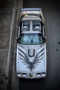 an old car is parked on the side of the road with wings painted on it