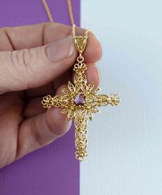 Looking for a meaningful and elegant piece of jewelry? Our handmade gold-plated solid silver filigree art cross pendant featuring a beautiful Amethyst gemstone is the perfect option. The cross is a Christian religious symbol that represents faith, good fortune, and protection. Our expert artisans have crafted the filigree art details inspired by nature, making each piece unique and special. The Amethyst gemstone is 6.00mm double-side faceted, checkerboard round-cut, adding a touch of luxury to t Spiritual Cross Necklace With Intricate Design, Gold Necklaces With Gemstone Cross Pendant, Gold Necklace With Gemstone Cross Pendant, Spiritual Cross Jewelry With Intricate Design, Yellow Gold Cross Necklace With Large Pendant, Gold Filigree Cross Pendant Necklace, Spiritual Crucifix Gemstone Jewelry, Ornate Cross Necklace With Intricate Design, Gemstone Cross Pendant Jewelry Gift